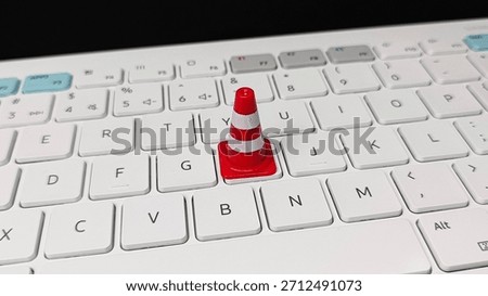 Website Maintenance and Technical Difficulties Concept with Orange Traffic Cone on Computer Keyboard Symbolizing System Error, Update Process, and Work in Progress. 