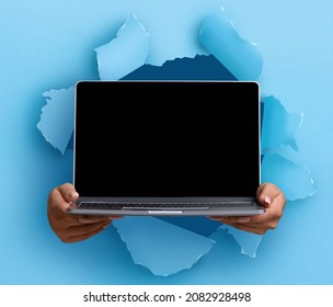 Website Promo, Great Offer. Female hands holding pc laptop with black empty screen showing device breaking through blue paper sheet. Blank gadget display with free copy space, mock up template