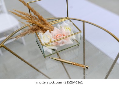 Wedding Accessories. Glass Box For Rings With Flowers And Dried Flowers And A Pen On A Wet Glass Table. Rain On The Wedding Day.High Quality Photo