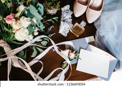 Wedding accessory bride. Stylish beige shoes, earrings, gold rings, flowers, garter, perfumes on table standing on wooden background. Letters from the bride and groom. flat lay. top view. - Powered by Shutterstock