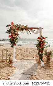 Wedding arch decorated with flowers for beach ceremony against the sea landscape. Tropical wedding ceremony in boho/ rustic style