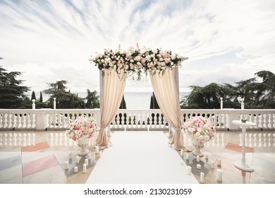 The wedding arch decorated with flowers stands in the luxurious area of the wedding ceremony. - Shutterstock ID 2130231059
