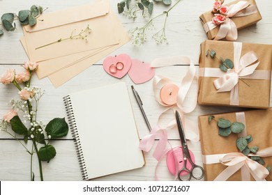 Wedding background with checklist. Paper planner and craft envelopes on white wooden table with lots of tender bridal stuff, top view
