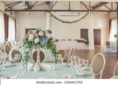 Wedding. Banquet. Bouquet with blue flowers. The chairs and round table for guests, served with cutlery, blue flowers and crockery and covered with a mint tablecloth. - Powered by Shutterstock