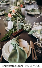Wedding banquet. The festive table is served with plates with napkins and name cards, glasses and cutlery, and decorated with flower arrangements and candles