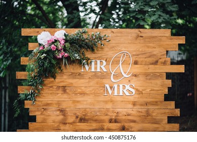 Wedding. Banquet. Mr. & Mrs. Signs On Wooden Board Decorated By Flowers And Greenery.