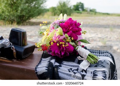 Wedding boho bouquet with pink magenta and yellow flowers. Bunch of flowers with white ribbon lies near vintage photo camera. Hippie wedding decoration - Powered by Shutterstock