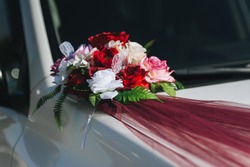 The Wedding Bouquet And Artificial Flower Decorations Are Attached With A Ribbon On The Hood Of The Car.