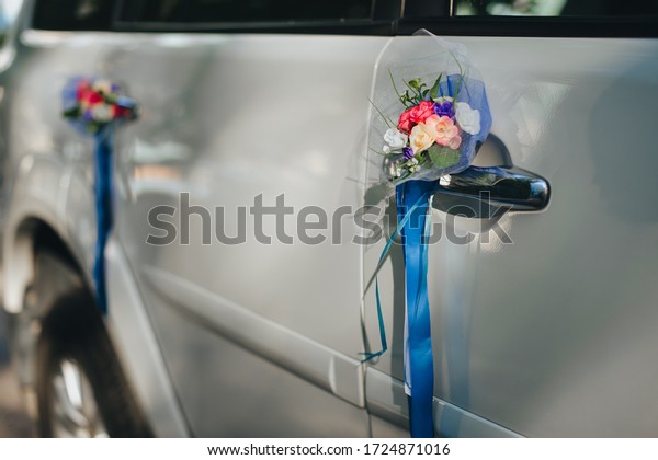A\
wedding bouquet of artificial flowers with a ribbon attached to the\
door of a white car close-up. Photography,\
concept.