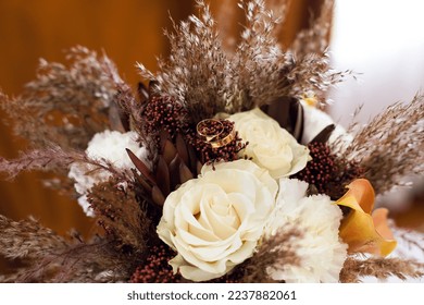 Wedding bouquet for the bride with gold wedding rings as a gift from white yellow orange different colors and dry grass indoors for a festive mood as an attribute of the wedding of the newlyweds - Powered by Shutterstock