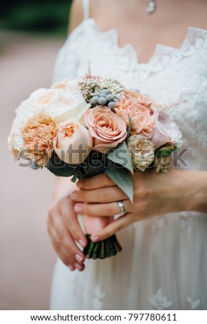 wedding bouquet in bride's hands. beige roses and peonies. The bride's dress is handmade.