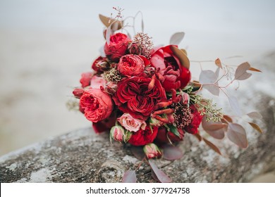 Wedding bouquet . The bride's bouquet. Bouquet of red and pink flowers, black berries and greenery, with a ribbon of color Marsala lies on a log by the lake - Powered by Shutterstock