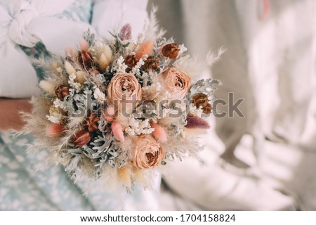 

wedding bouquet of dried flowers in the hands of a florist