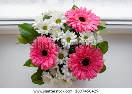 Wedding bouquet of flowers near the window. Close-up with space for the label. Winter window with flowers. Bouquet with gerberas and daisies on the winter window. Holiday background. Copy space