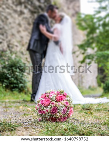 Wedding bouquet in front of newlyweds wedding couple inbackground, kissing or holding hands in love Shallow depth bokeh