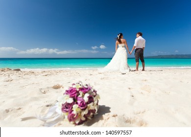 Wedding bouquet on wedding couple background, kissing at the beach 