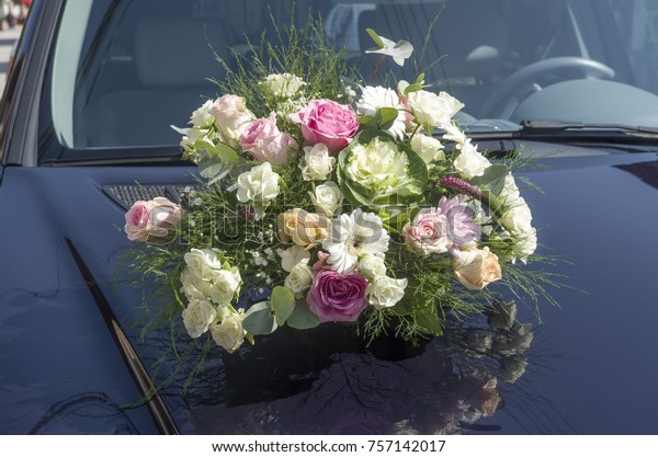 Wedding\
bouquet on the front cover of a blue\
car\

