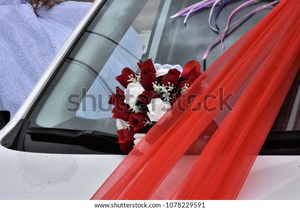 A wedding bouquet of red and white artificial\
flowers with scarlet tape on a car for the newlyweds  . Negev,\
Israel, spring, April 2018