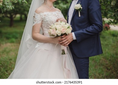 Wedding bouquet of roses in the hands of the bride and groom. Bridal bouquet of roses in the hands of the woman. Bouquet of lavander and roses: cream, white and pink. Groom boutonniere with white rose