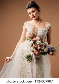 Wedding Bouquet. Studio Portrait Of Beautiful Bride In Gorgeus Wedding Dress With Large Cascade Bouquet On Golden Background. 