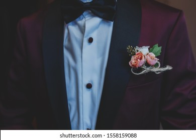 Wedding boutonniere for the groom . Wine red color suite. Wedding details in close-up view. Groom in a jacket,