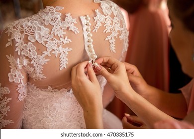 Wedding. Bridesmaid preparing bride for the wedding day. Bridesmaid helps fasten a wedding dress the bride before the ceremony. Luxury bridal dress close up. Best wedding morning. Wedding concept - Powered by Shutterstock