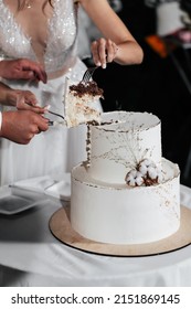 A wedding cake. Milk-colored cake decorated with cotton beads and gold leaf on a dark background