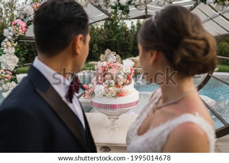 Wedding cake on a table with unrecognizable couple of espouses.