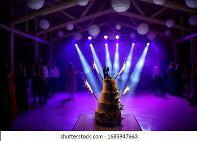 A Wedding Cake With Silhouette Of Bride And Groom With Light Show On The Background