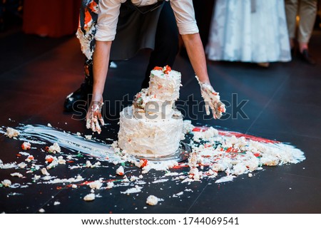 Wedding cake that fell to the floor. The waiter's hands collect it.