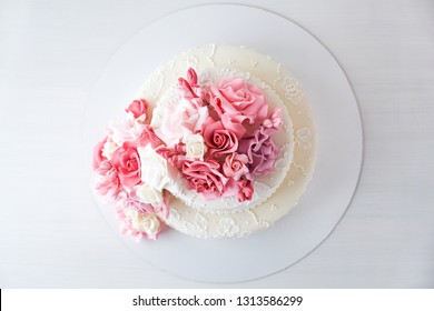 Wedding Cake Top View Decorated With Pink Flowers On A White Wooden Background.