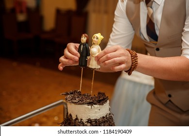 A Wedding Cake Topper. Funny Cake Decoration. Figurines Of Bride And Groom. Close-up Of Groom Hands