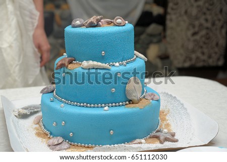 Wedding cake in white and blue combination, adorned with flowers, ribbons and butterflies