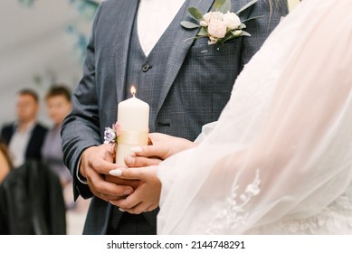 The wedding candle in the hands of the bride and groom. the candle is the family hearth at the wedding. Candle in hand at the wedding.