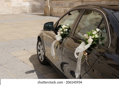 A wedding car decorated with bouquets of white roses