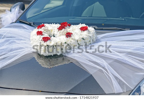Wedding car\
decorated with flowers. Floral wedding decoration on car. Flower\
decoration on the front of wedding\
car