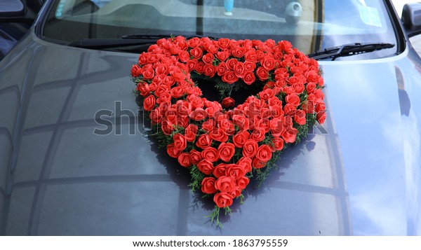 The wedding car is decorated with flowers. Floral\
wedding decoration in the car. Floral decoration on the front of\
the red rose wedding car