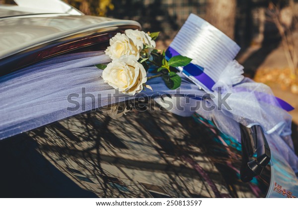 Wedding car decoration. A black wedding car\
decorated with white roses. Flower bouquet on a wedding car.\
limousine wedding\
bouquet