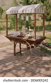 Wedding celebration. Buffet with beautiful decorations. Sweets, cookies, berries and fruits. Macaroons. Wooden cart on grass. Nature. Pastel colors. Dishes and serving. Catering