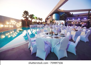 Wedding celebration dinner at sea side hotel near swimming pool surrounded with palms
