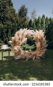 Wedding Ceremony In The Garden For The Bride And Groom. The Arch Is Made Of Fresh Flowers And Dead Wood, Reeds. Outdoor Wedding Ceremony.
