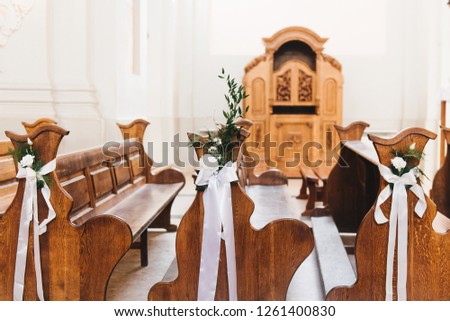 Wedding in the church. bright temple. Shallow depth of field. white ornaments on benches and chairs. Wedding greens and flowers.