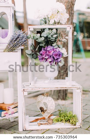 Wedding composition of the white wooden crates with vase of colourful flowers in it. The crates are decorated with handmade hearts.