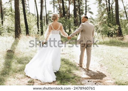 Similar – Image, Stock Photo The bride and groom go through the forest hand in hand. Happy bride and groom holding hands and walking in forest on wedding day.