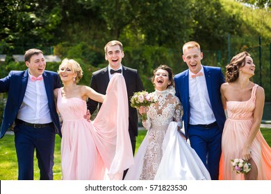 Wedding couple, bridesmads and groomsmen  pose happy on green lawn