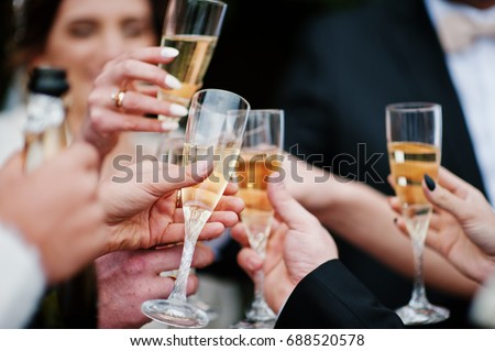 Wedding couple, bridesmaids and groomsmen drinking champagne outside.