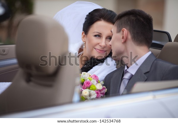 wedding couple in car bride and groom smiling in\
wedding car outdoors. happy loving newlywed couple embracing at\
bridal day. wife and husband enjoy moment of happiness. Passionate\
married couple