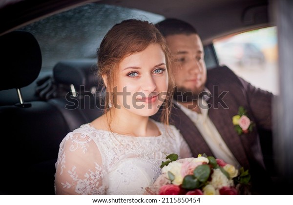 A wedding couple in a car. The bride and groom\
in a white dress hug in the\
car