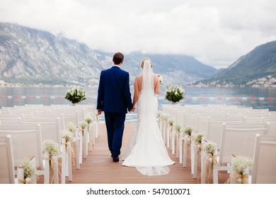 Wedding Couple At Wedding Ceremony Back View. Mountains And Sea Background In Montenegro