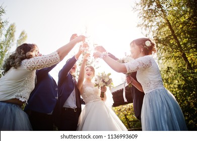 Wedding couple and groomsmen with bridesmaids drinking champagne outdoors in the park or garden.